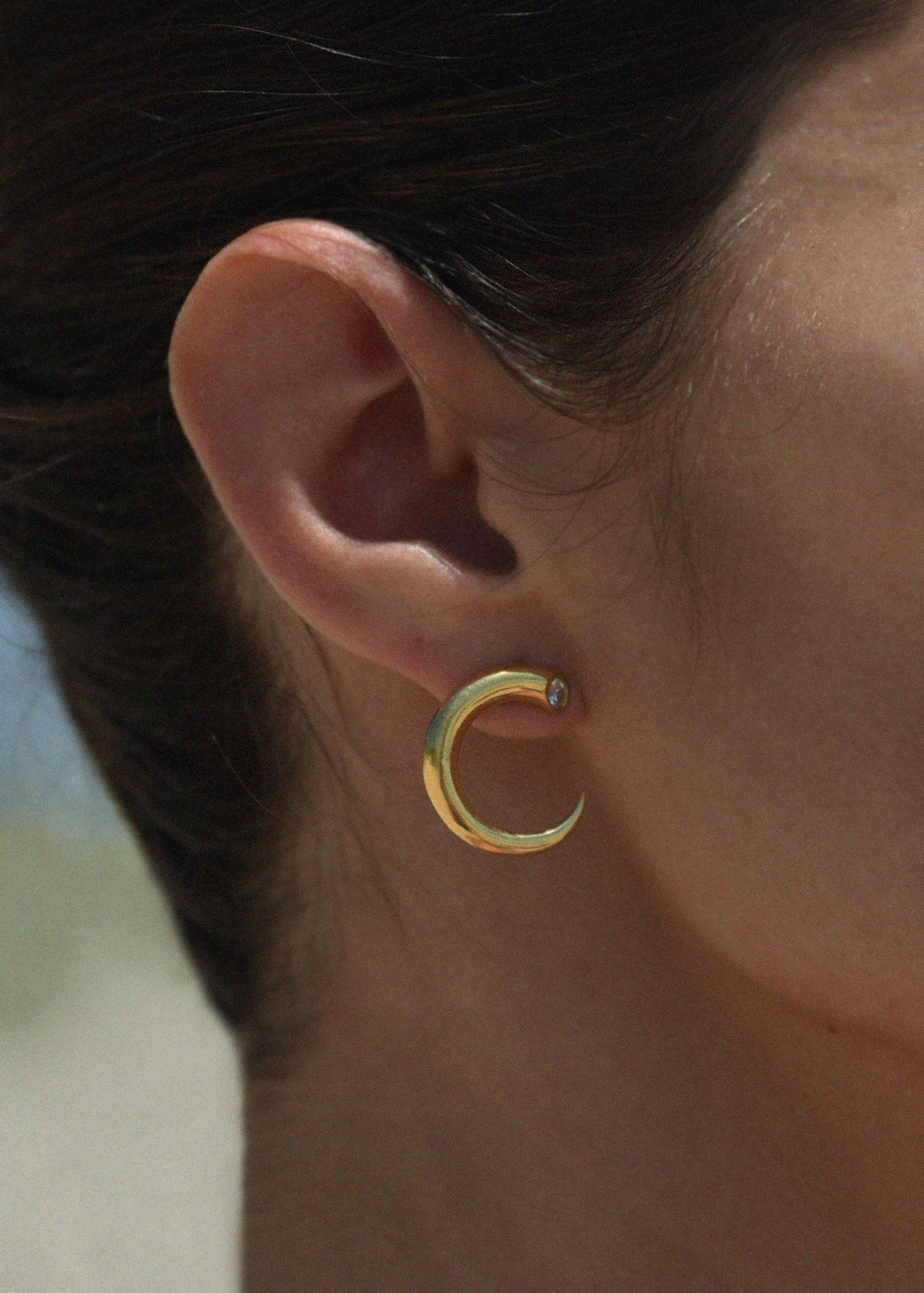 Gold hoop earring worn by a person with a blurred background